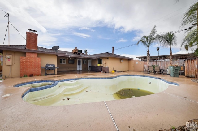 view of swimming pool with a patio area, grilling area, a pool with connected hot tub, and fence