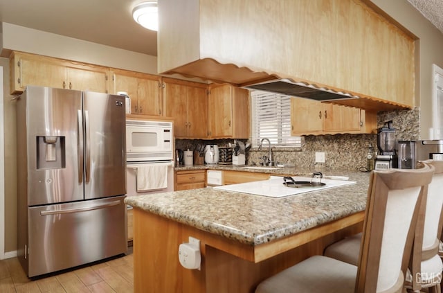 kitchen with tasteful backsplash, white appliances, a peninsula, and a sink