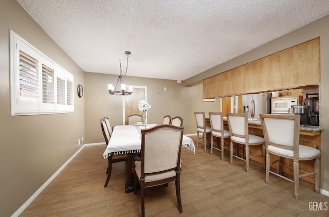 dining room with baseboards, a textured ceiling, an inviting chandelier, and wood finished floors