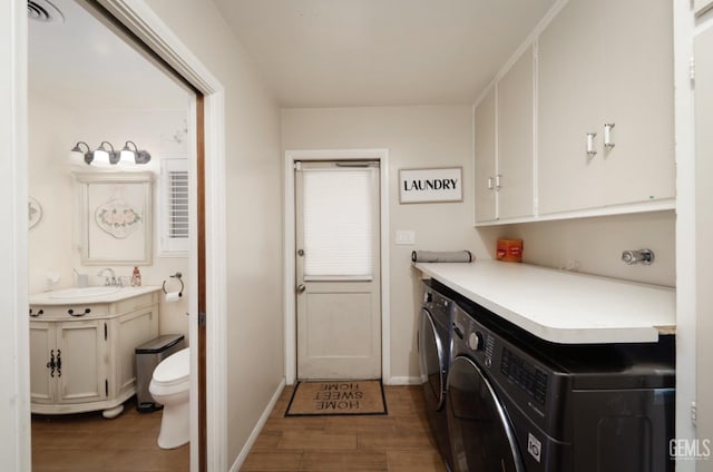 washroom with a sink, visible vents, separate washer and dryer, and wood finished floors