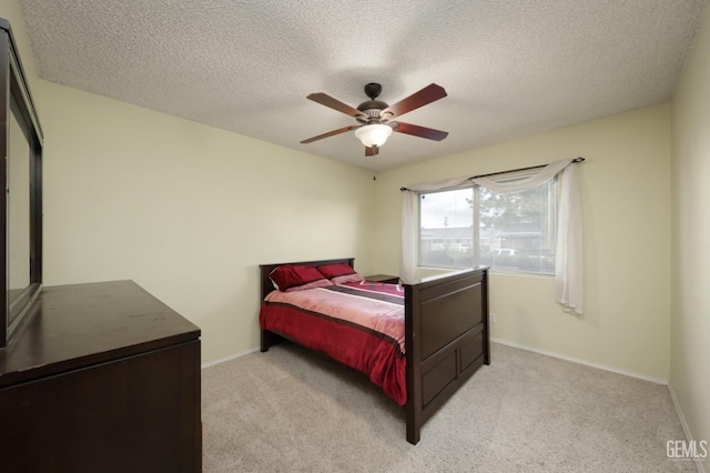 bedroom featuring a textured ceiling, light colored carpet, baseboards, and ceiling fan