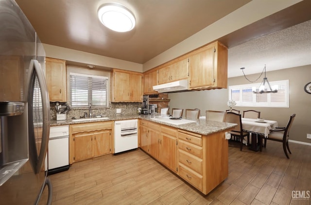 kitchen featuring light wood-style flooring, stainless steel refrigerator with ice dispenser, a sink, under cabinet range hood, and a peninsula