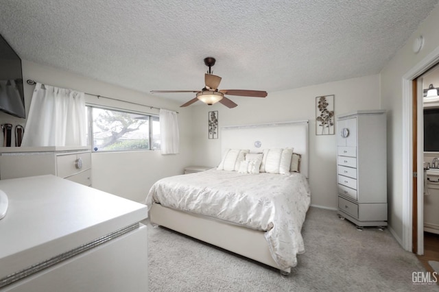 bedroom featuring ceiling fan, a textured ceiling, baseboards, and light carpet