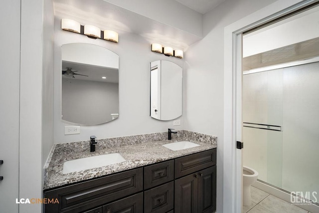 bathroom with a shower with shower door, tile patterned floors, vanity, toilet, and ceiling fan