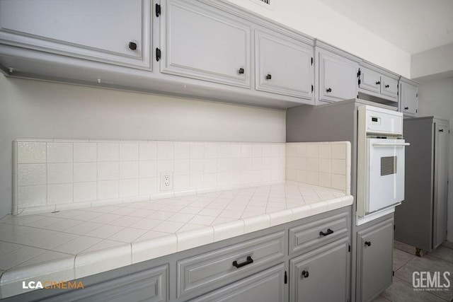 kitchen with tile counters, tile patterned flooring, and white oven