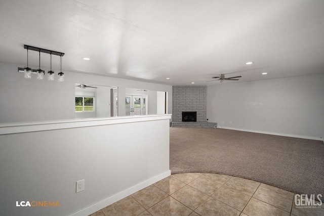 unfurnished living room featuring ceiling fan, light colored carpet, and a fireplace