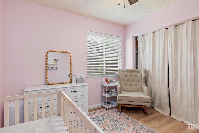 5928 Dyce Way, Bakersfield, CA 93306 - bedroom featuring light wood-style flooring, a crib, a textured ceiling, and ceiling fan