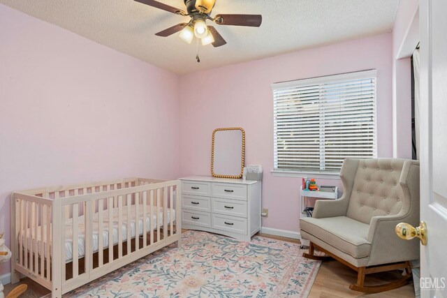 5928 Dyce Way, Bakersfield, CA 93306 - bedroom featuring light wood-style floors, a ceiling fan, a nursery area, and a textured ceiling