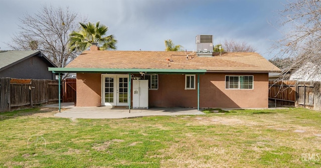 rear view of property featuring french doors, a yard, a patio, and cooling unit