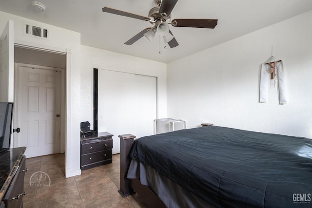 tiled bedroom featuring ceiling fan and a closet