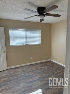 2509 Pacheco Rd, Bakersfield, CA 93304 - empty room with a textured ceiling, plenty of natural light, a ceiling fan, wood finished floors, and baseboards