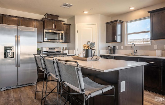 kitchen with sink, a kitchen breakfast bar, stainless steel appliances, and a center island