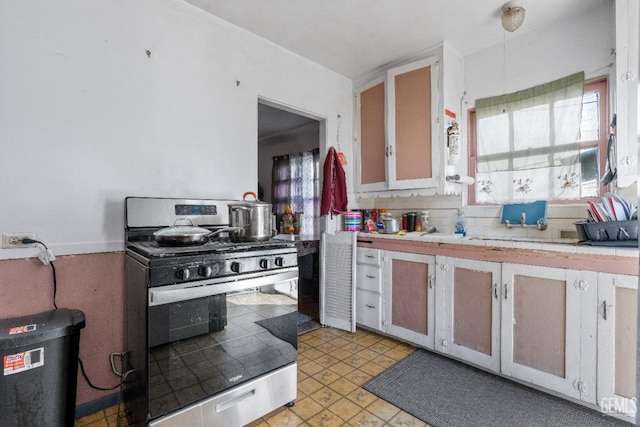 kitchen with tile counters, tasteful backsplash, and stainless steel range with gas cooktop