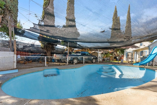 view of pool with fence and a water slide