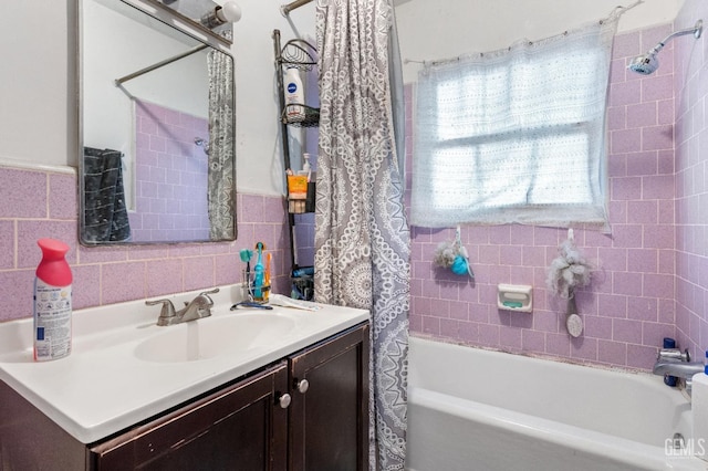 full bath featuring wainscoting, tile walls, vanity, and shower / bath combo