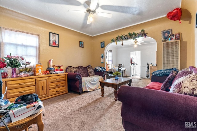 living room featuring light carpet, arched walkways, and a ceiling fan