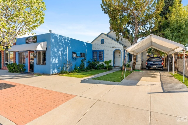 view of front of property featuring a detached carport, concrete driveway, a front yard, and fence