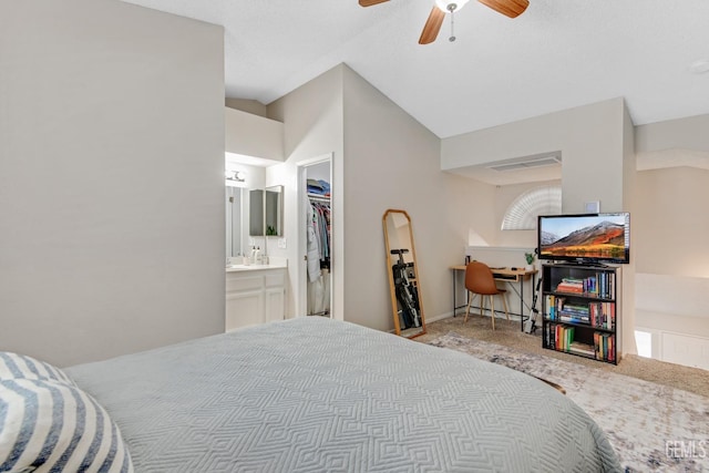 bedroom featuring a spacious closet, vaulted ceiling, ceiling fan, light carpet, and ensuite bathroom