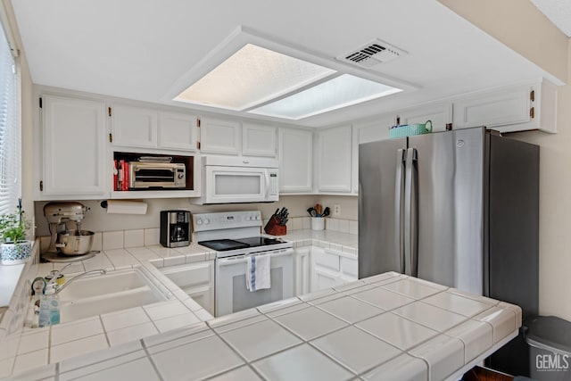 kitchen with sink, white cabinets, white appliances, and tile countertops