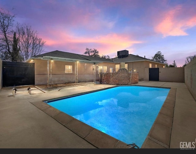 pool at dusk featuring a patio