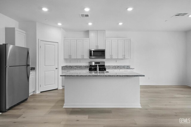 5016 Beaverhead Ave, Bakersfield, CA 93306 - kitchen with stainless steel appliances, an island with sink, light stone counters, light wood finished floors, and recessed lighting