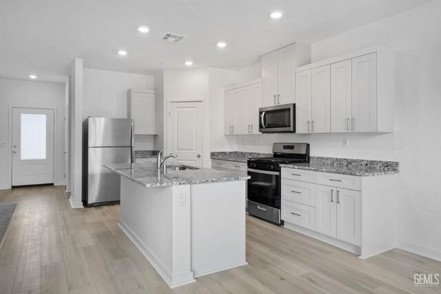 5016 Beaverhead Ave, Bakersfield, CA 93306 - kitchen featuring stainless steel appliances, light wood-style floors, light stone counters, a kitchen island with sink, and recessed lighting