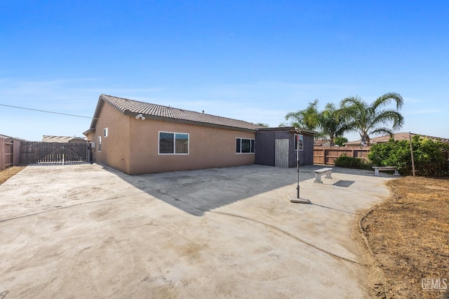 back of property featuring fence, a gate, a patio area, and stucco siding