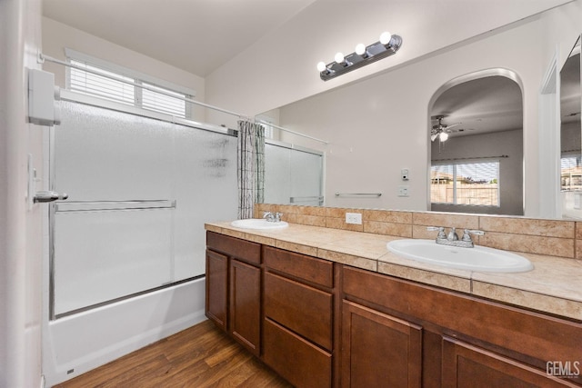 full bath featuring ceiling fan, combined bath / shower with glass door, a sink, and wood finished floors