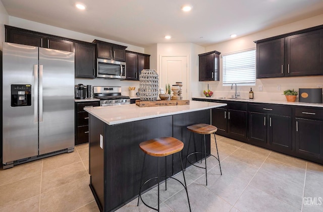 kitchen featuring sink, light tile patterned floors, a kitchen breakfast bar, a kitchen island, and stainless steel appliances