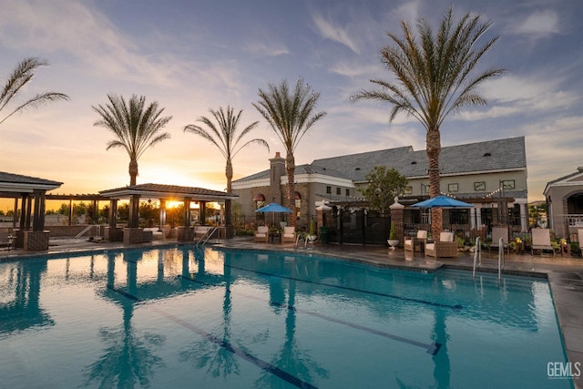 pool at dusk featuring a gazebo and a patio