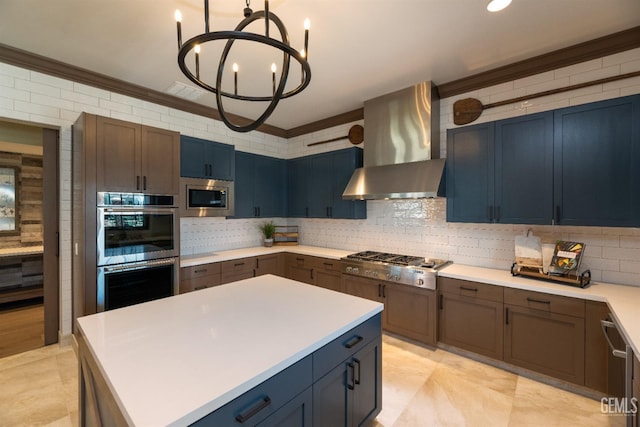 kitchen featuring a kitchen island, tasteful backsplash, stainless steel appliances, an inviting chandelier, and wall chimney exhaust hood