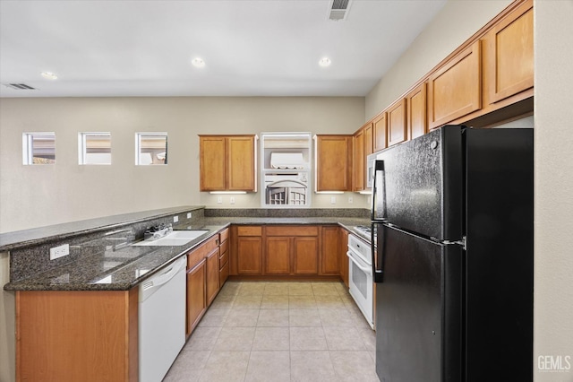 kitchen featuring sink, dark stone counters, and white appliances