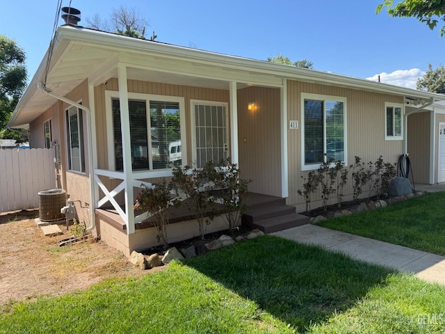 view of front of property featuring central air condition unit, a porch, fence, and a front yard