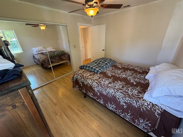 bedroom featuring visible vents, a ceiling fan, wood finished floors, and a closet