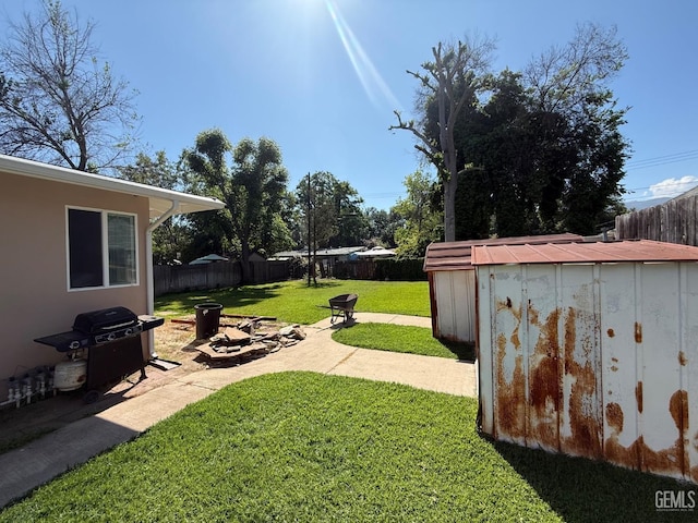 view of yard featuring a shed, a fenced backyard, an outbuilding, a patio, and a fire pit