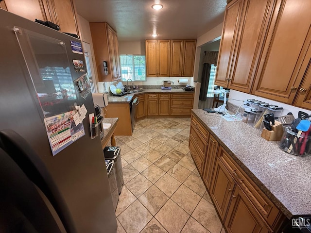 kitchen with stainless steel appliances, brown cabinetry, and a sink