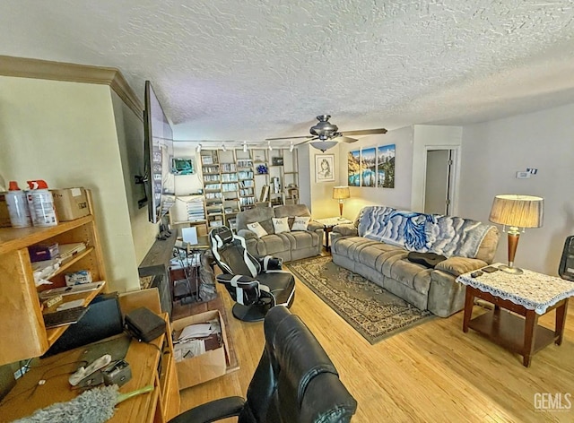 living room featuring a ceiling fan, a textured ceiling, and wood finished floors