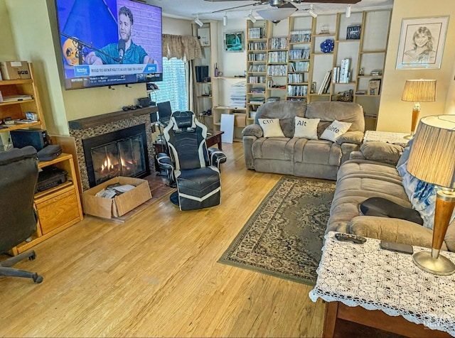 living room with a ceiling fan, a glass covered fireplace, and wood finished floors