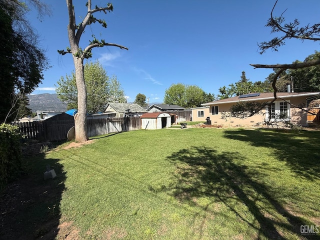 view of yard with a storage shed, an outbuilding, and a fenced backyard