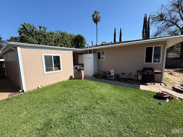 rear view of house with fence and a yard