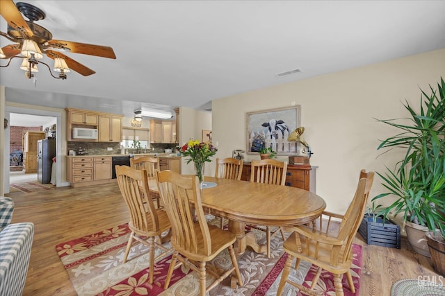 dining space featuring visible vents, ceiling fan, and light wood finished floors