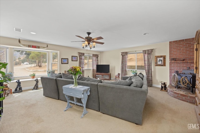 living area featuring a wood stove, a wealth of natural light, carpet flooring, and visible vents