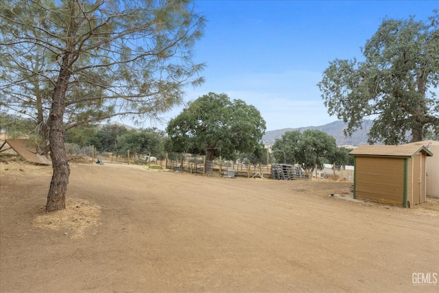 view of yard featuring a shed, a mountain view, and an outbuilding