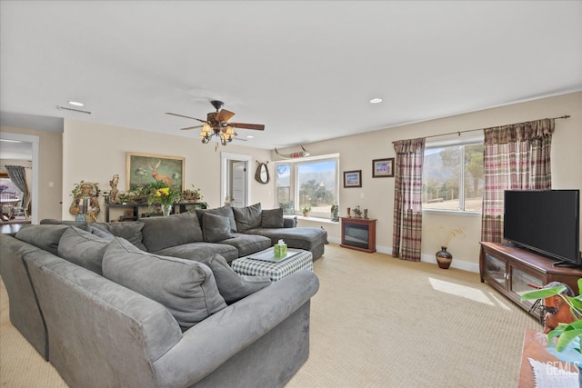 carpeted living area with ceiling fan and baseboards