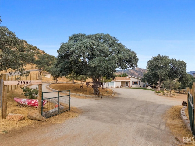 view of road with dirt driveway, a gated entry, and a mountain view