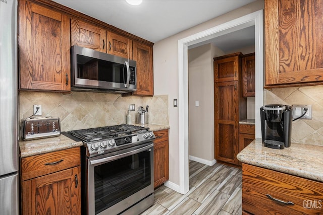 4512 Orrick Ct, Bakersfield, CA 93308 - kitchen featuring appliances with stainless steel finishes, tasteful backsplash, light stone counters, and brown cabinets