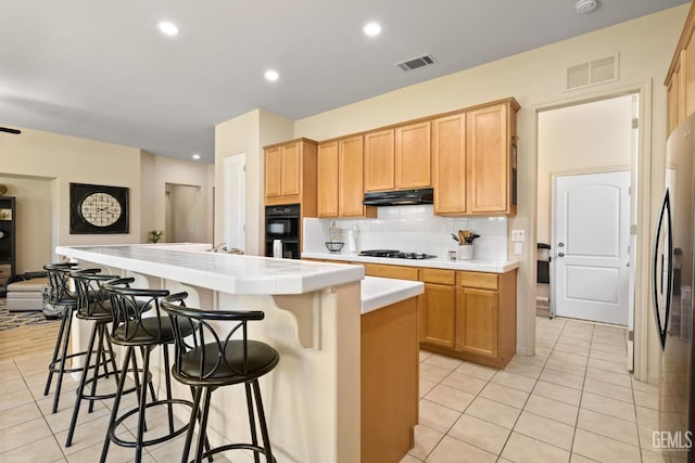 11901 Kimelford Dr, Bakersfield, CA 93312 - kitchen with tile counters, gas stovetop, light tile patterned floors, decorative backsplash, and under cabinet range hood