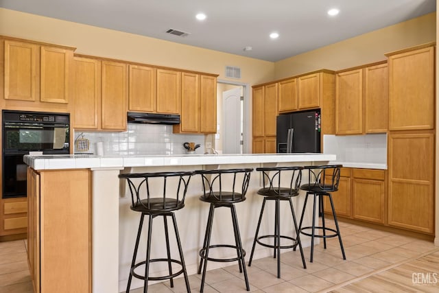 11901 Kimelford Dr, Bakersfield, CA 93312 - kitchen featuring black appliances, under cabinet range hood, tasteful backsplash, a breakfast bar, and a spacious island