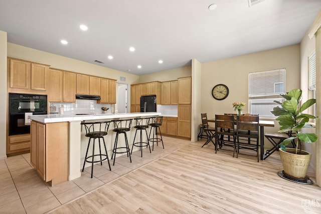 11901 Kimelford Dr, Bakersfield, CA 93312 - kitchen featuring black appliances, under cabinet range hood, light brown cabinets, a large island, and a breakfast bar area