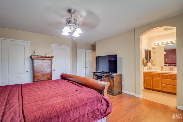 10126 Pyramid Peak Dr, Bakersfield, CA 93311 - bedroom featuring arched walkways, light wood finished floors, connected bathroom, a ceiling fan, and multiple closets